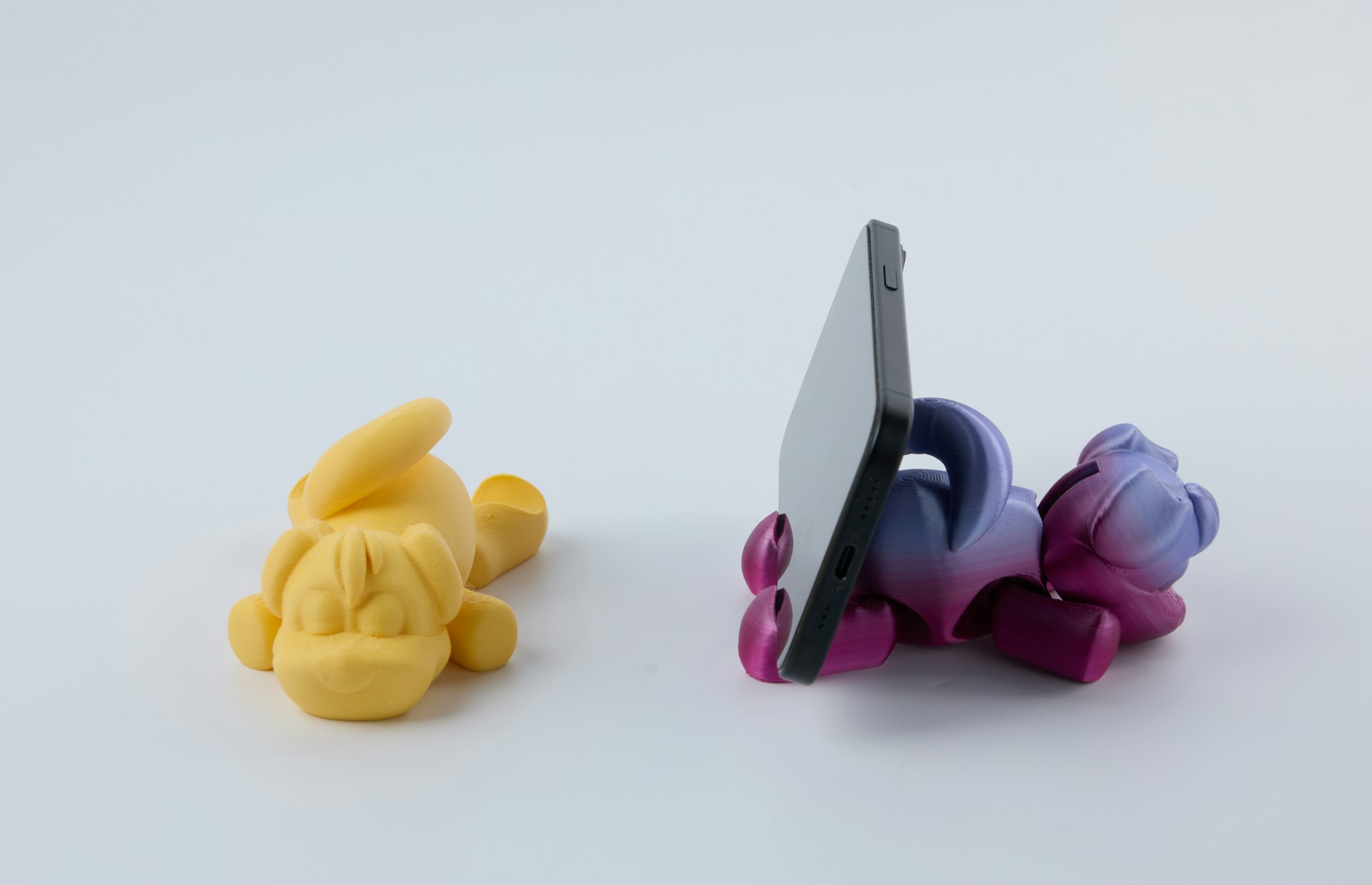 A phone rests on a bear-shaped phone holder.